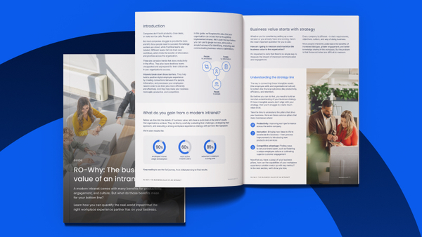 A professional man and woman in a modern office looking at a digital tablet together, symbolizing workplace collaboration and the use of an intranet platform.