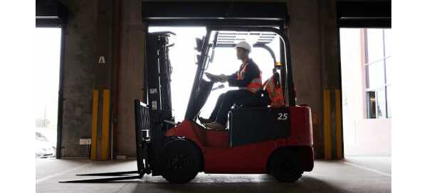 A worker driving a lift truck in a factory warehouse.